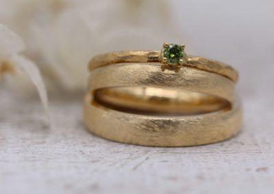Absolut zeitlose Trauringe mit unempfindlicher Oberfläche namens Düne, dazu Vorsteckring Olivi mit grünem Stein
