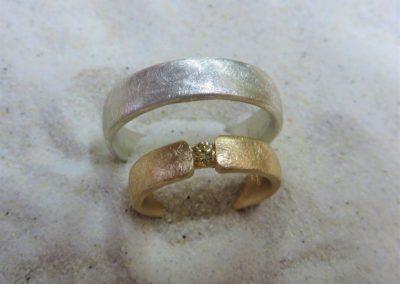 Schlichte zweifarbige Trauringe in Silber und Roségold in eismatt mit gelbem Brillanten.