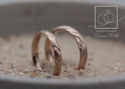 Braune Trauringe aus Haselnussgold bzw. Toffeegold mit Buchtmuster.