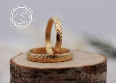 Federartige Trauringe mit Federblattmuster aus Gold.